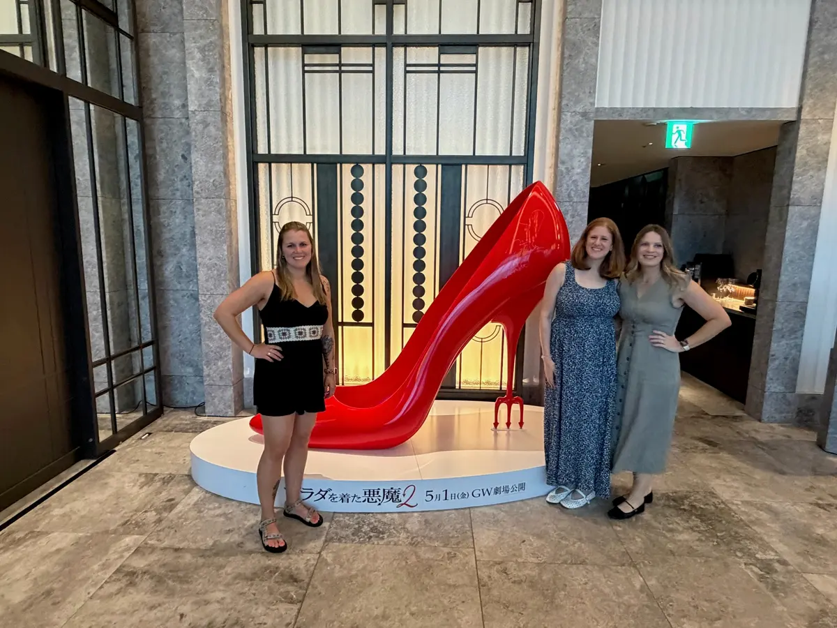 Sarah, Caitlin, and Ashley posing with a giant red shoe display.