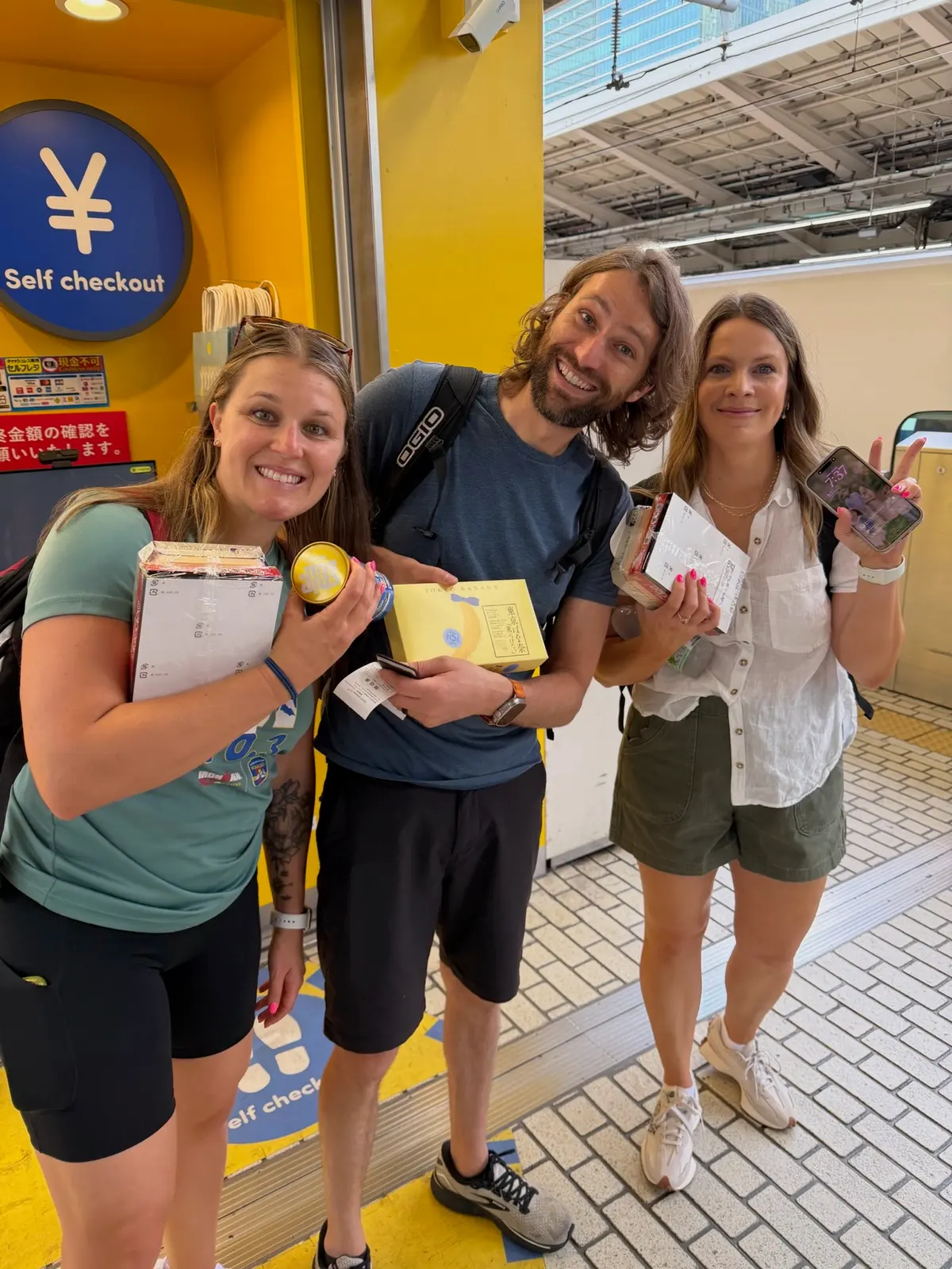 Sarah, Zach, and Ashley holding tickets and snacks at a train station.