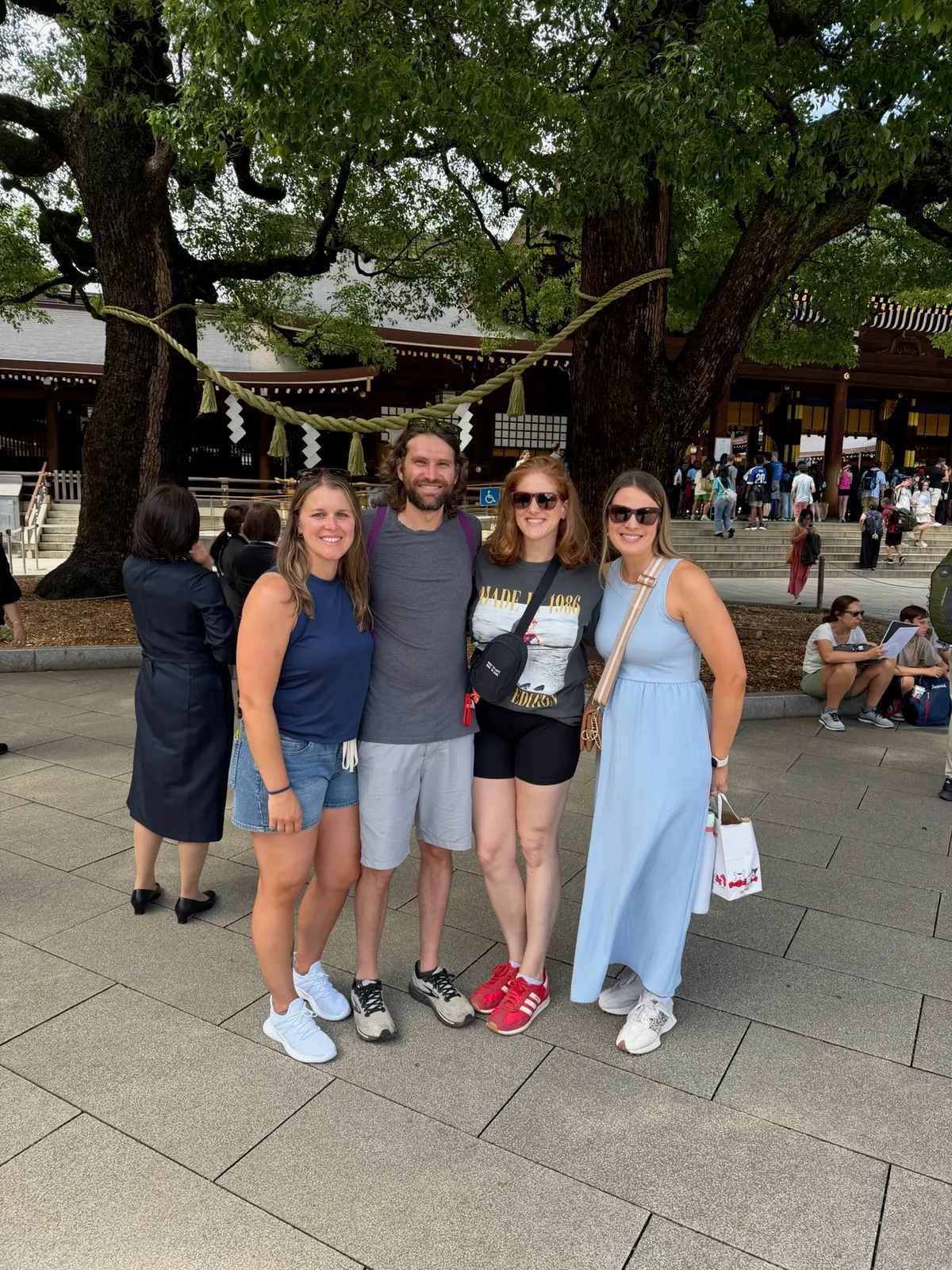 Group photo near trees and a shrine walkway in Tokyo.