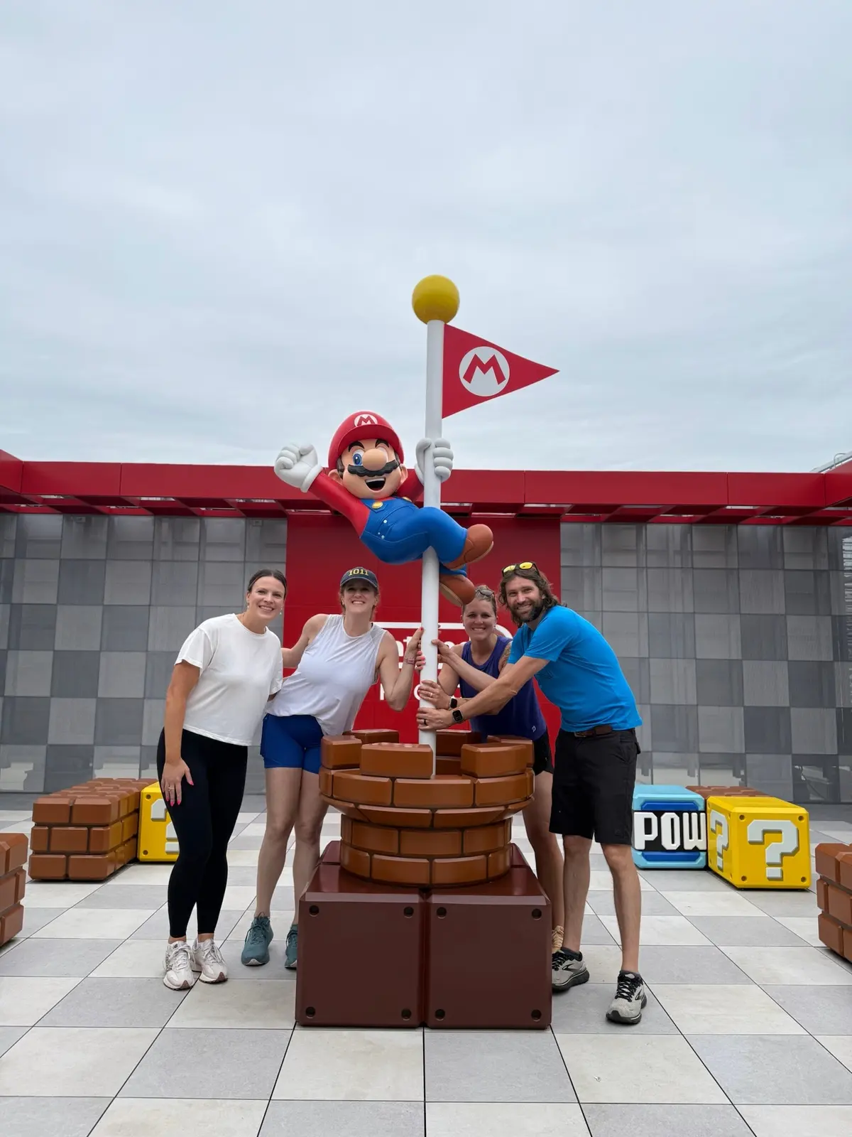 The group posing with a large Mario display at Nintendo Store Kyoto.