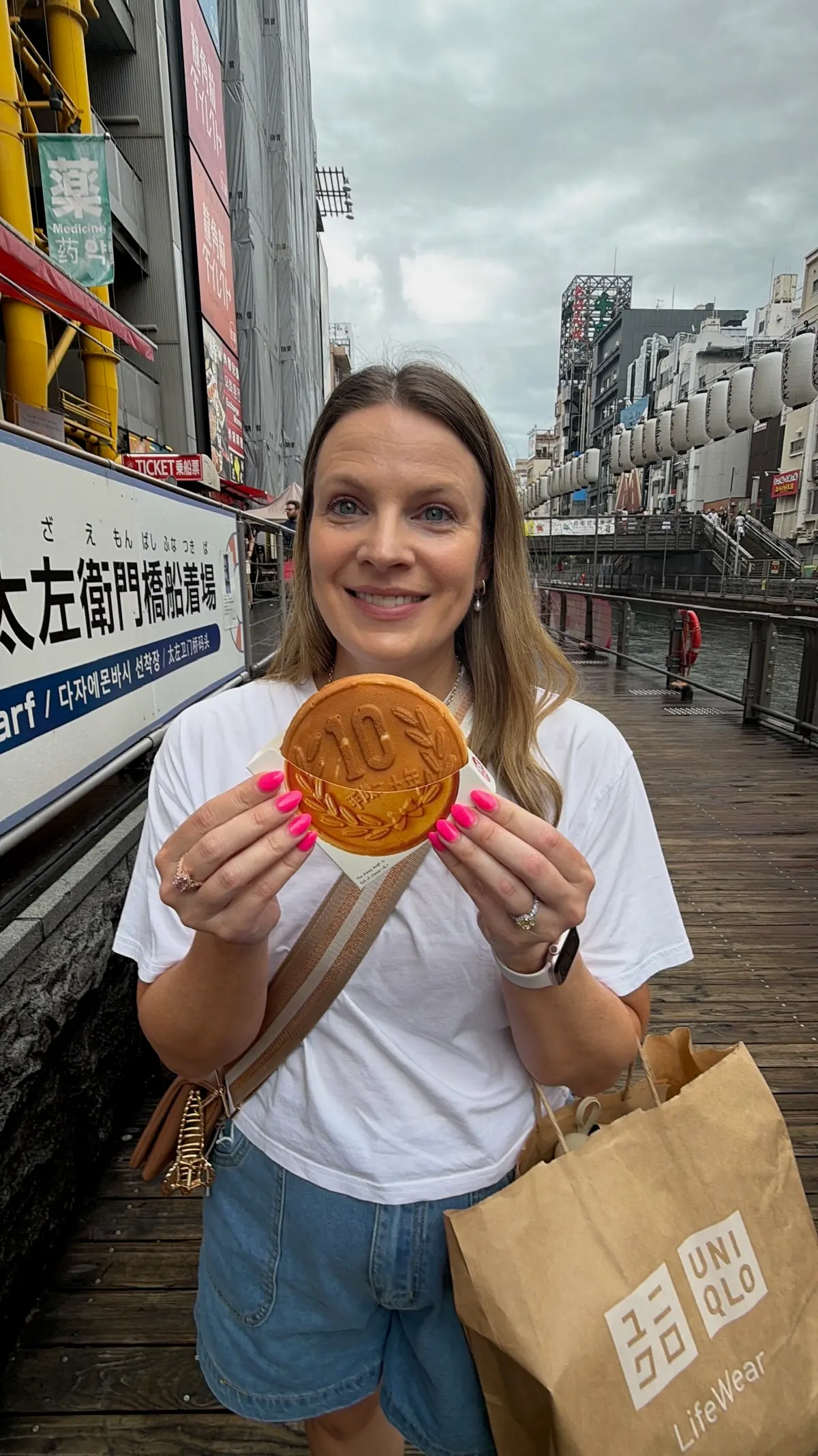 Ashley holding a ten-yen cheese waffle in Dotonbori.