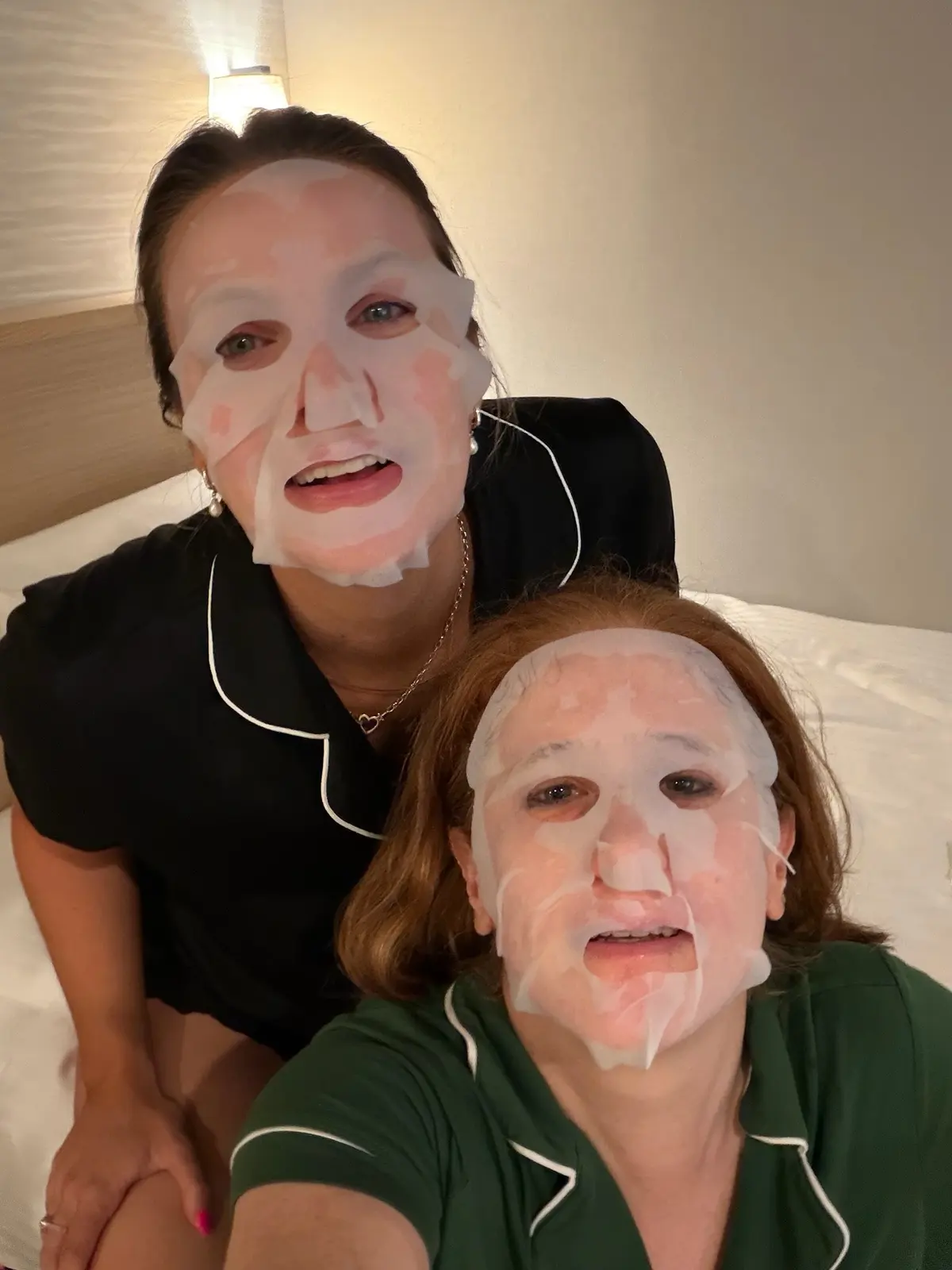 Sarah and Caitlin wearing sheet masks in the hotel room.