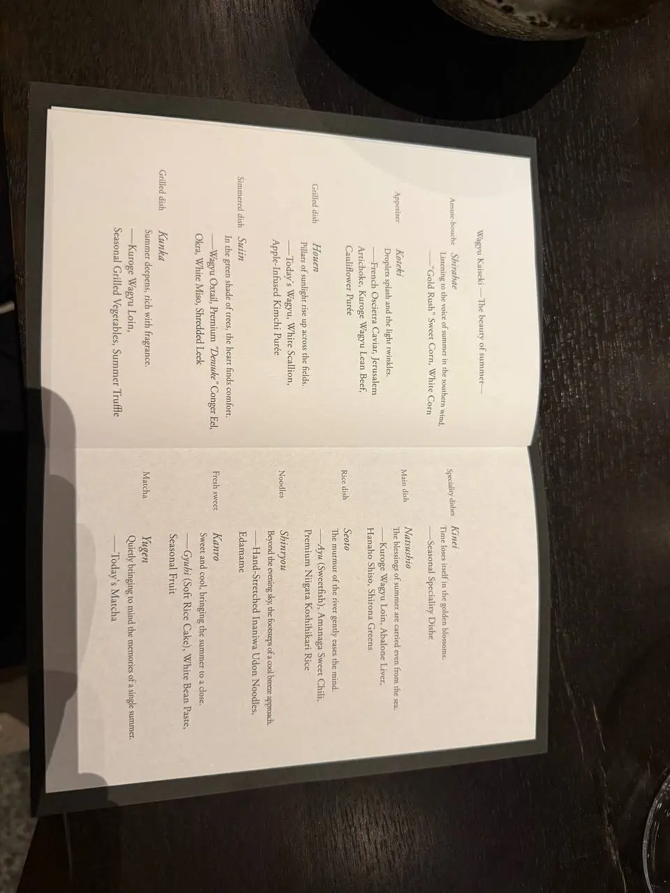 Printed wagyu kaiseki dinner menu on a dark table in Osaka.